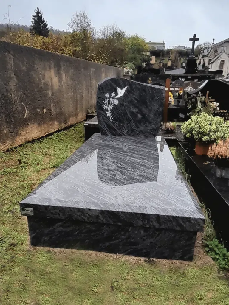 Monument funéraire en granit gris foncé avec stèle gravée d'une colombe