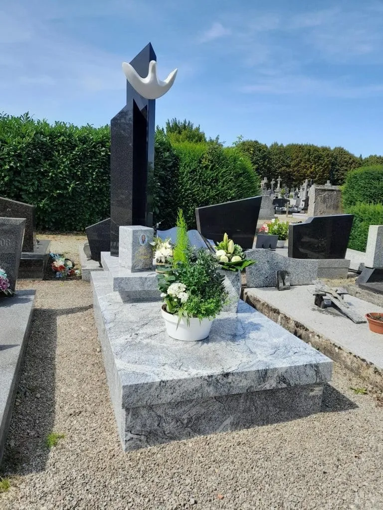 Monument funéraire contemporain en granit gris et noir avec sculpture de colombe